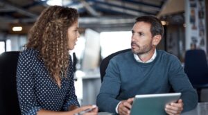 Two professionals discussing work with a digital tablet in a modern office.