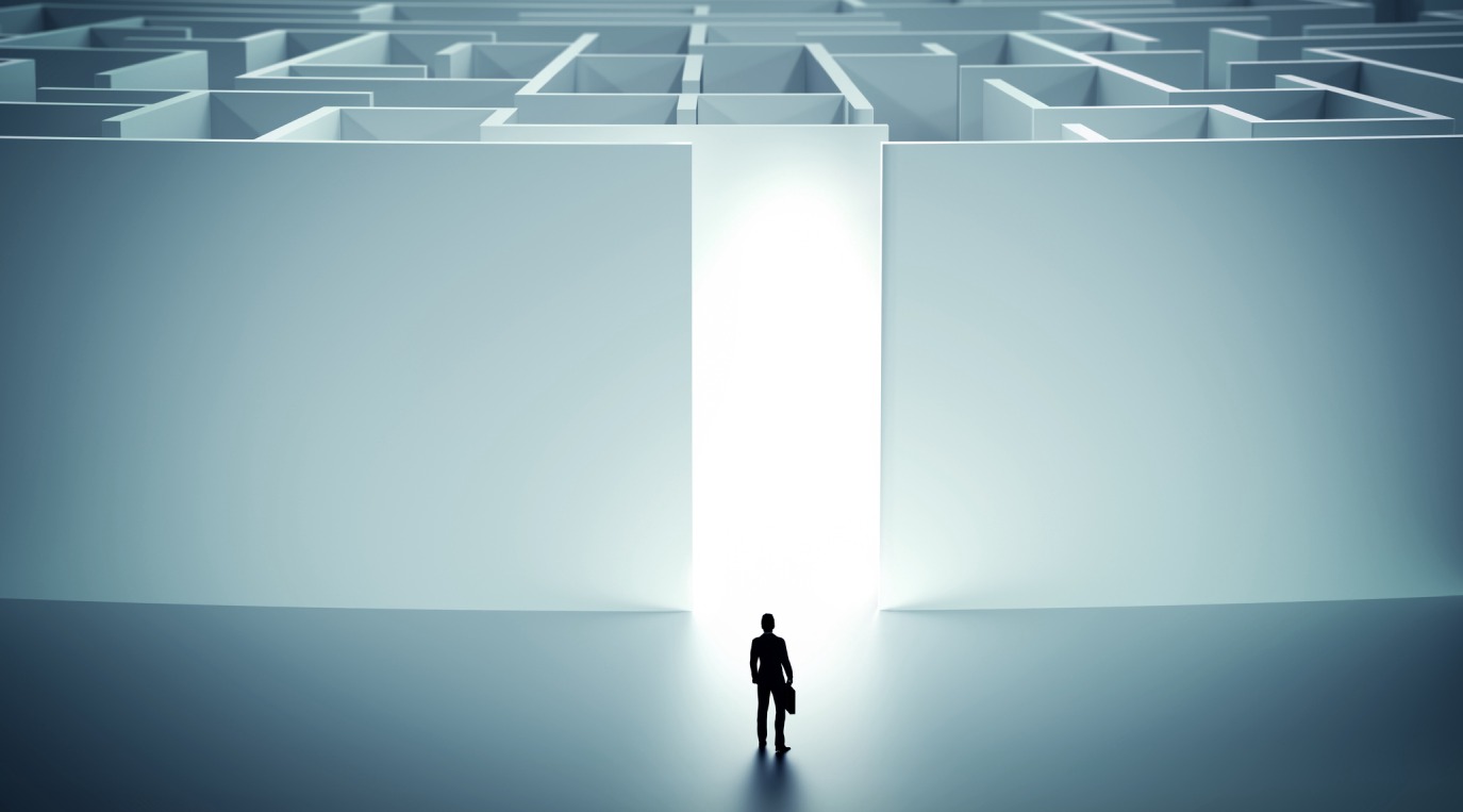 A person facing a bright exit in a dark maze, symbolizing solution and escape.
